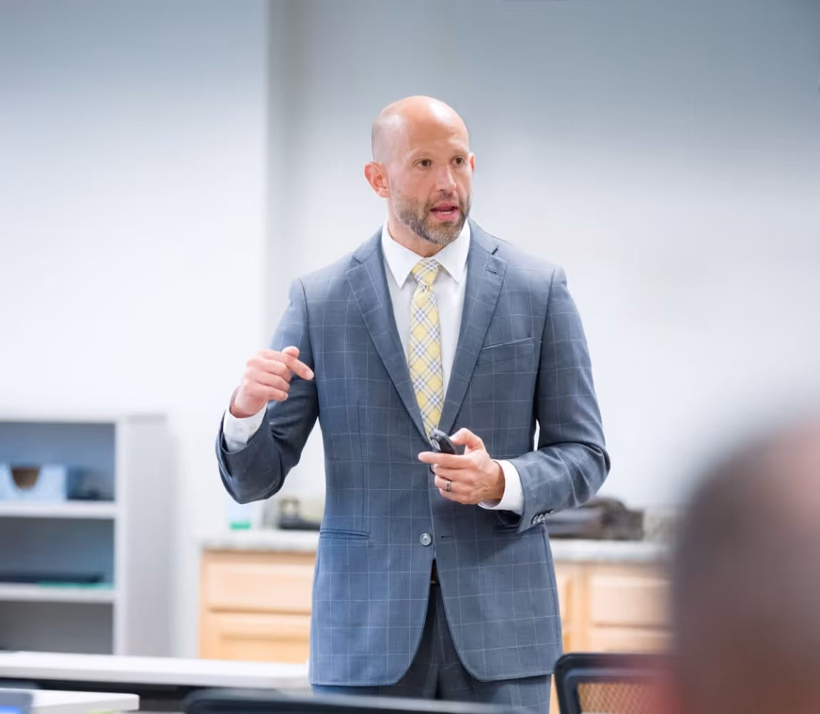 Image of Christopher Mannino intently conversing with a room full of students. 