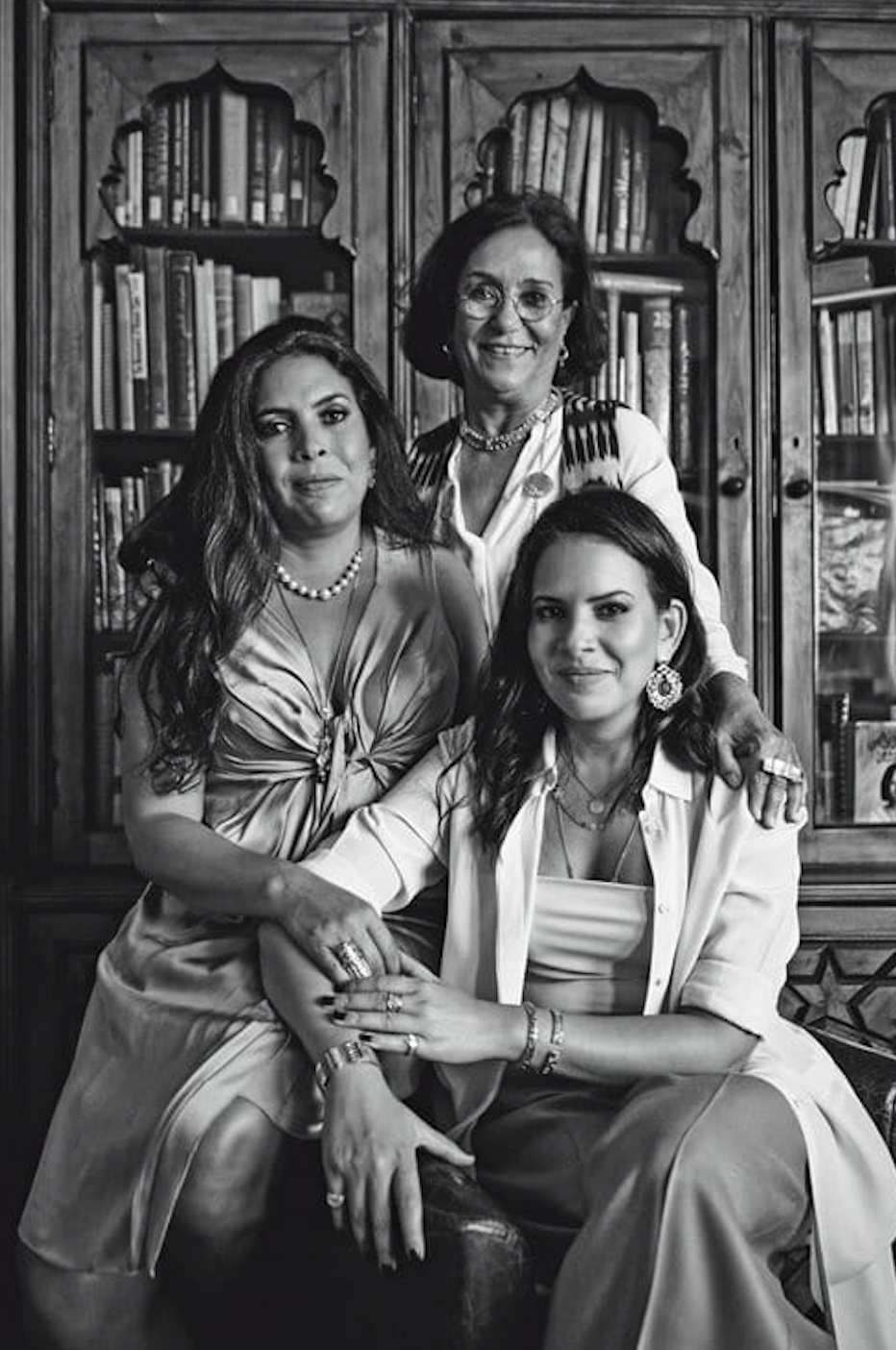 A black and white portrait of three women smiling at the camera.