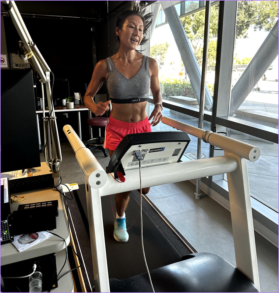 A woman is running on a treadmill in front of a computer.