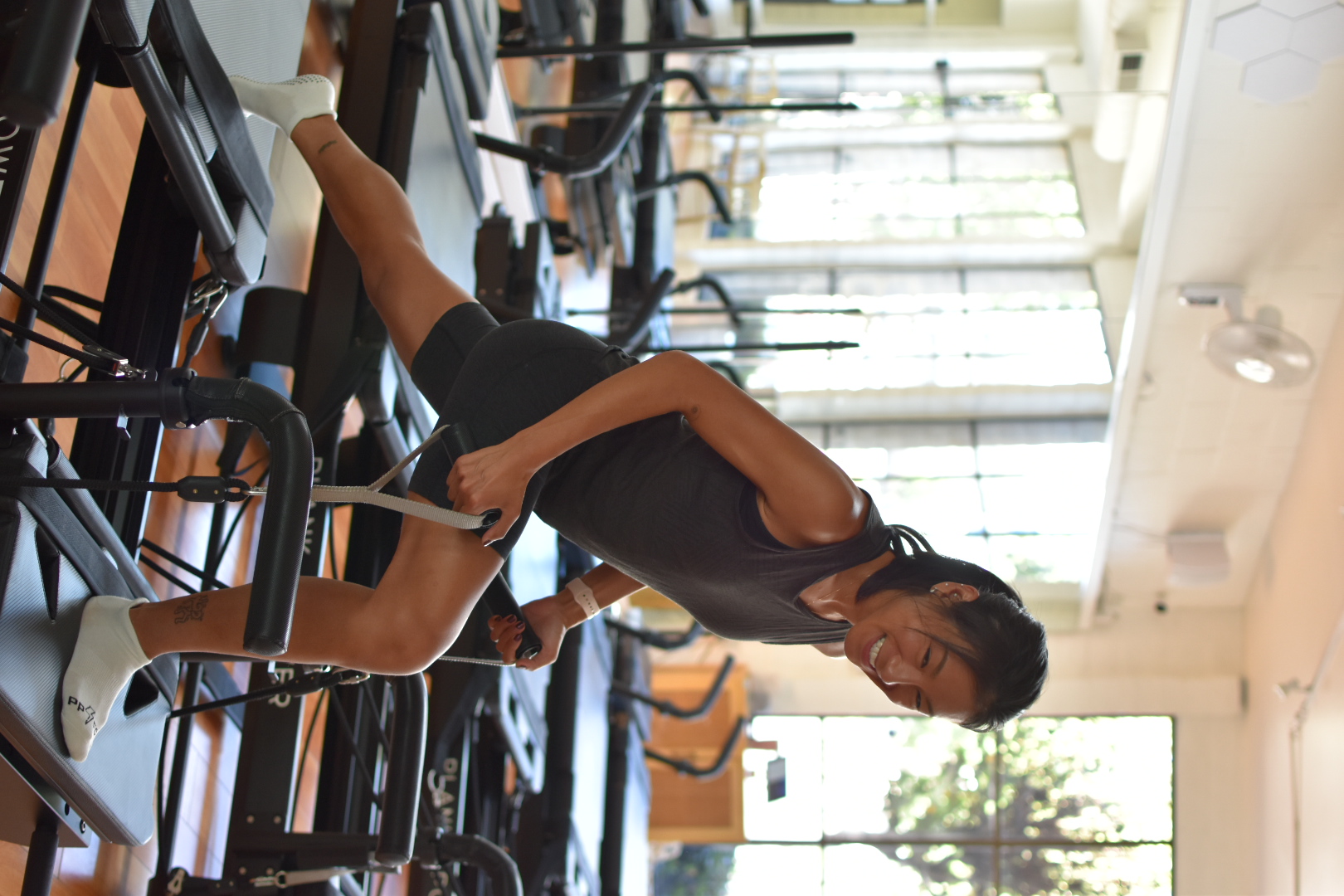 A woman is smiling while working out on a machine.