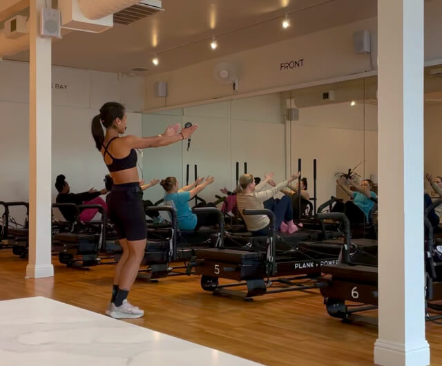 A woman in a black tank top is working out on a stationary bike.