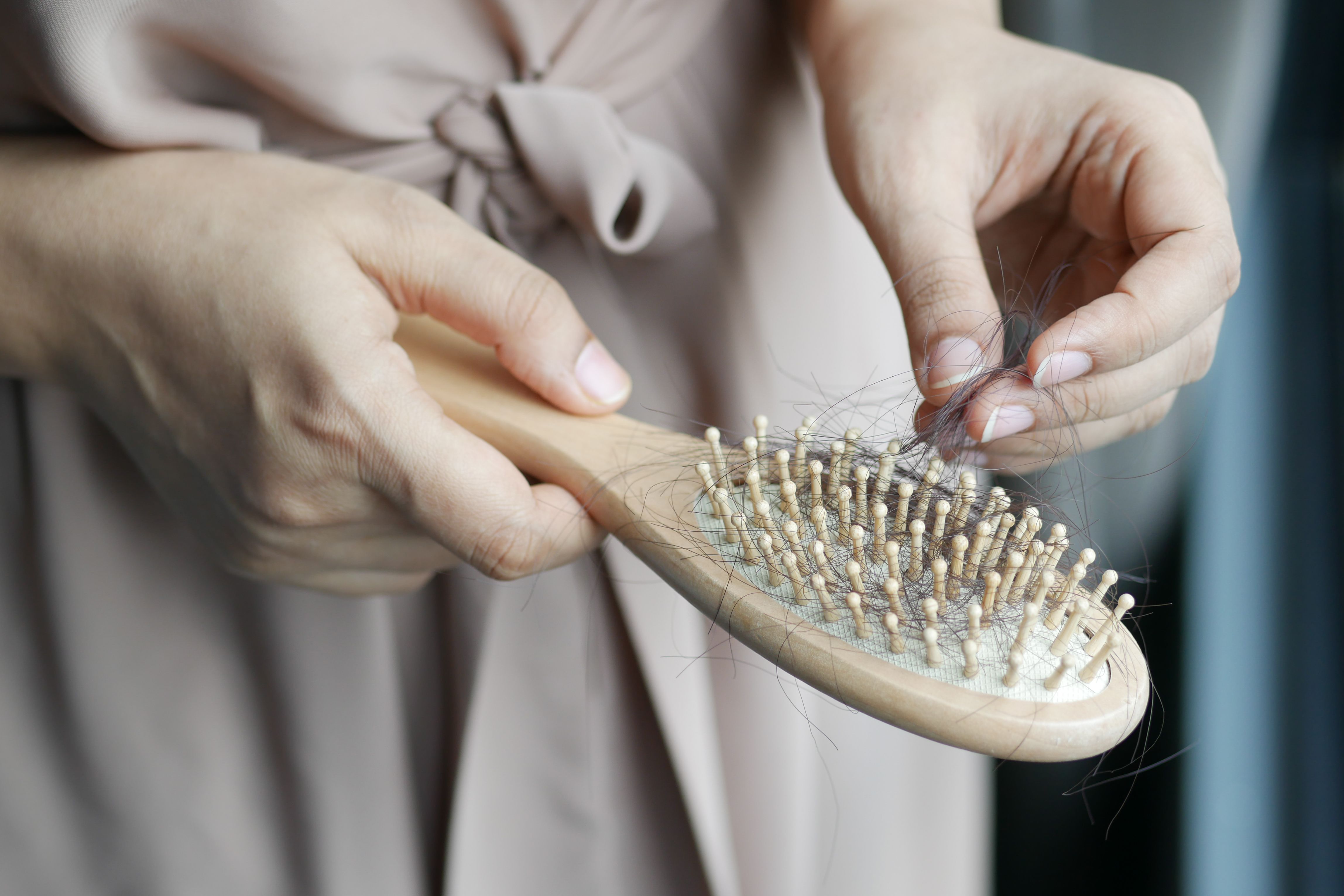 Une personne retire les cheveux coincés dans une brosse en bois