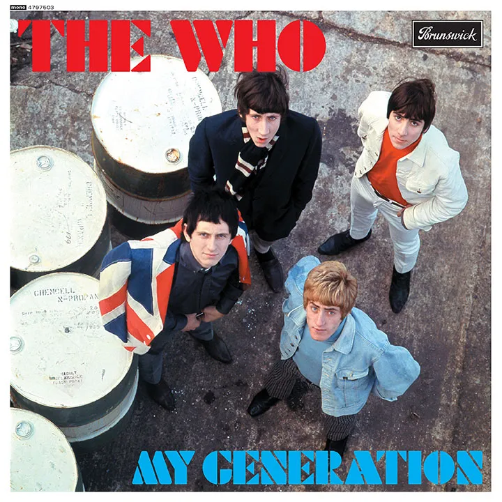 This image is the album cover of The Who’s single ‘My Generation’. It features a photograph of the four band members standing on a concrete surface looking upwards at the camera lens. Three of them have dark hair and one has light blonde hair. They are wearing a mix of denim and dark clothing. ‘The Who’ is in a red stencil font at the top left of the composition and ‘My Generation’ is in a smaller blue stencil font in the bottom right.