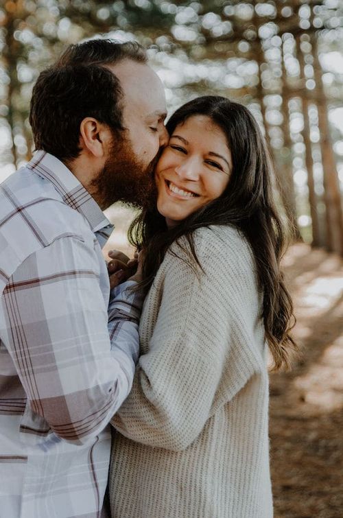 engaged couple with woods in the background