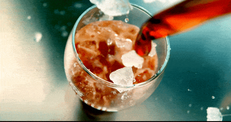 Ice and Coca Cola fall elegantly in super slow motion into an ice cold glass, very refreshing.