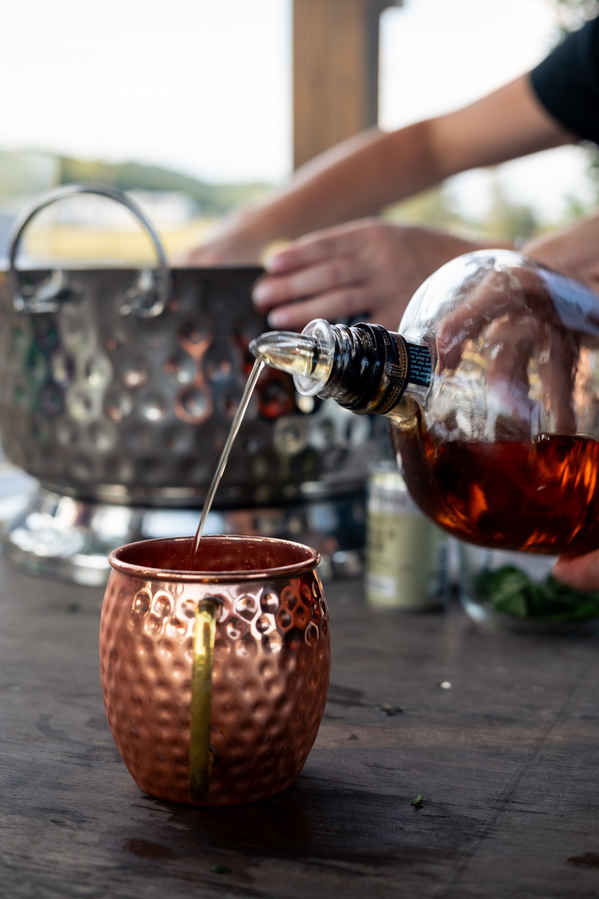 A bourbon cocktail being poured into a copper mug