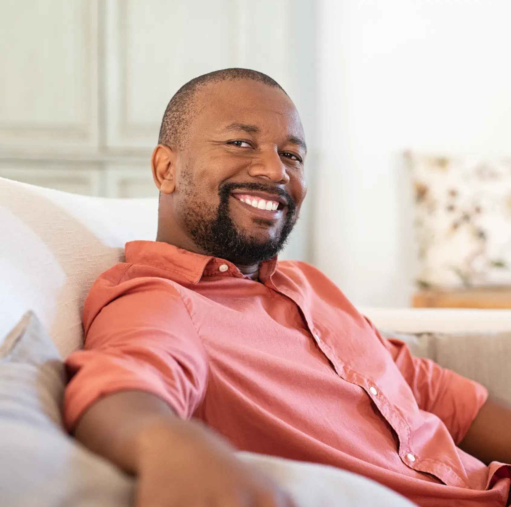 A man sitting on a couch smiling at the camera.