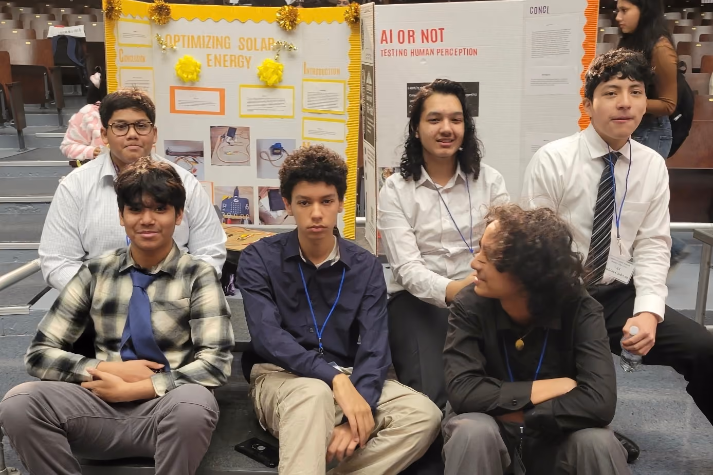Students posing in front of science fair project boards