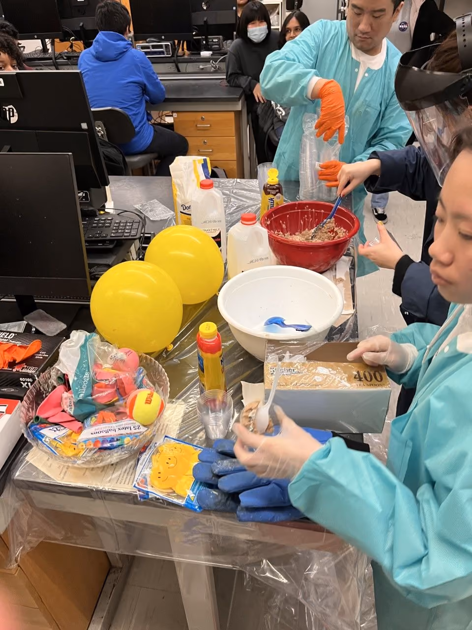 Students in lab coats mixing materials during a science classroom experiment