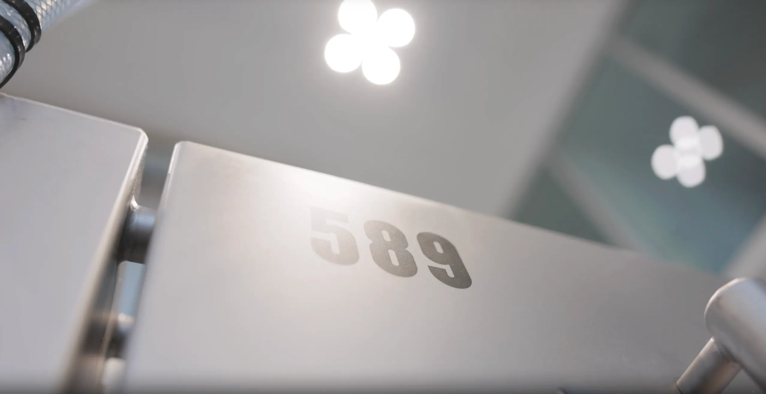 Close-up of a metallic surface with the number 589 printed on it, under soft overhead lights.