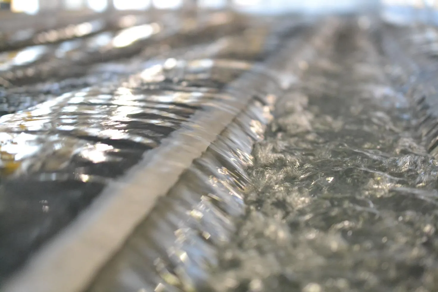 Close-up of flowing water with ripples and bubbles reflecting light.