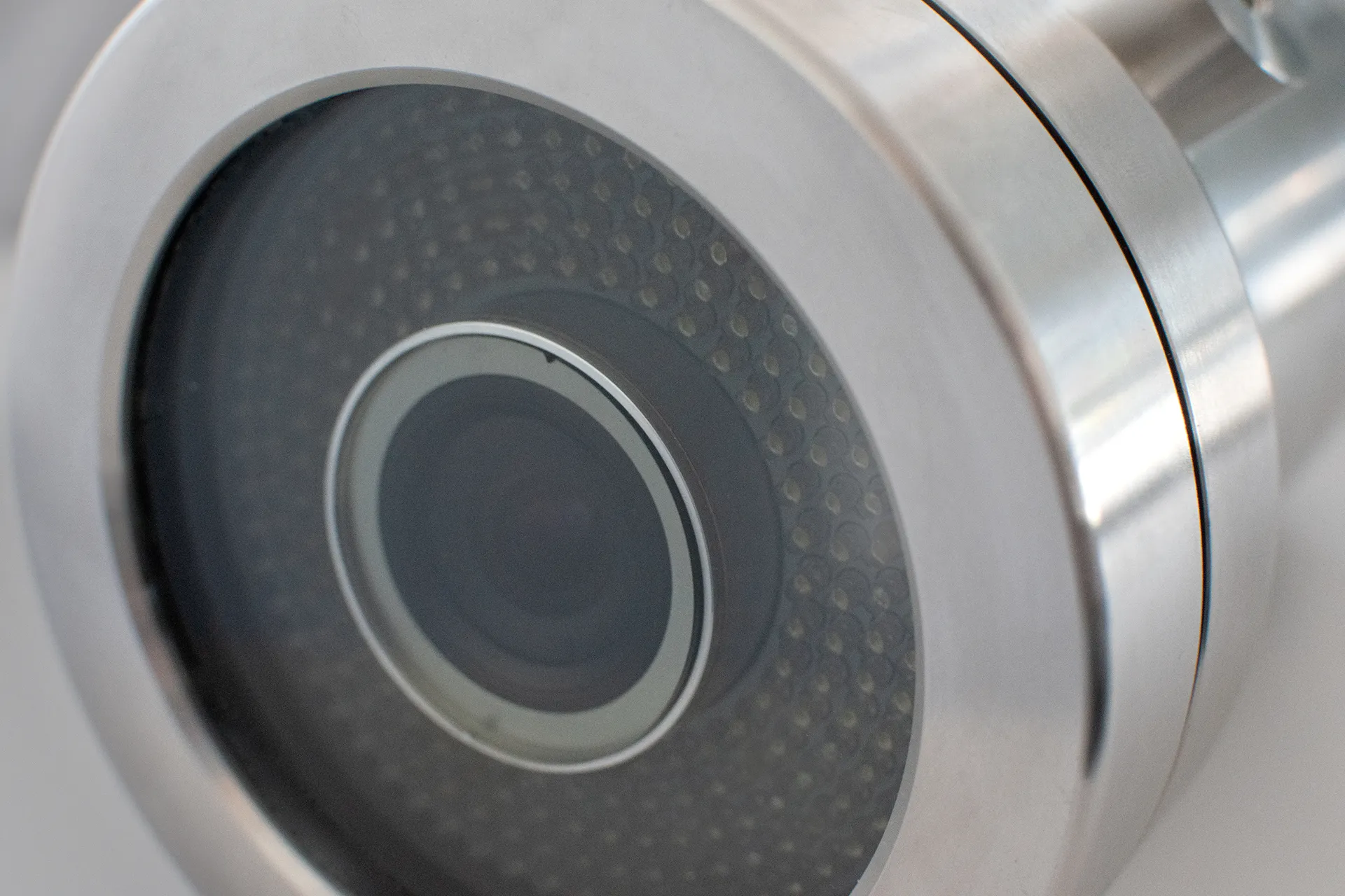 Close-up of a metallic security camera lens with concentric rings and an array of small LED lights surrounding the lens.