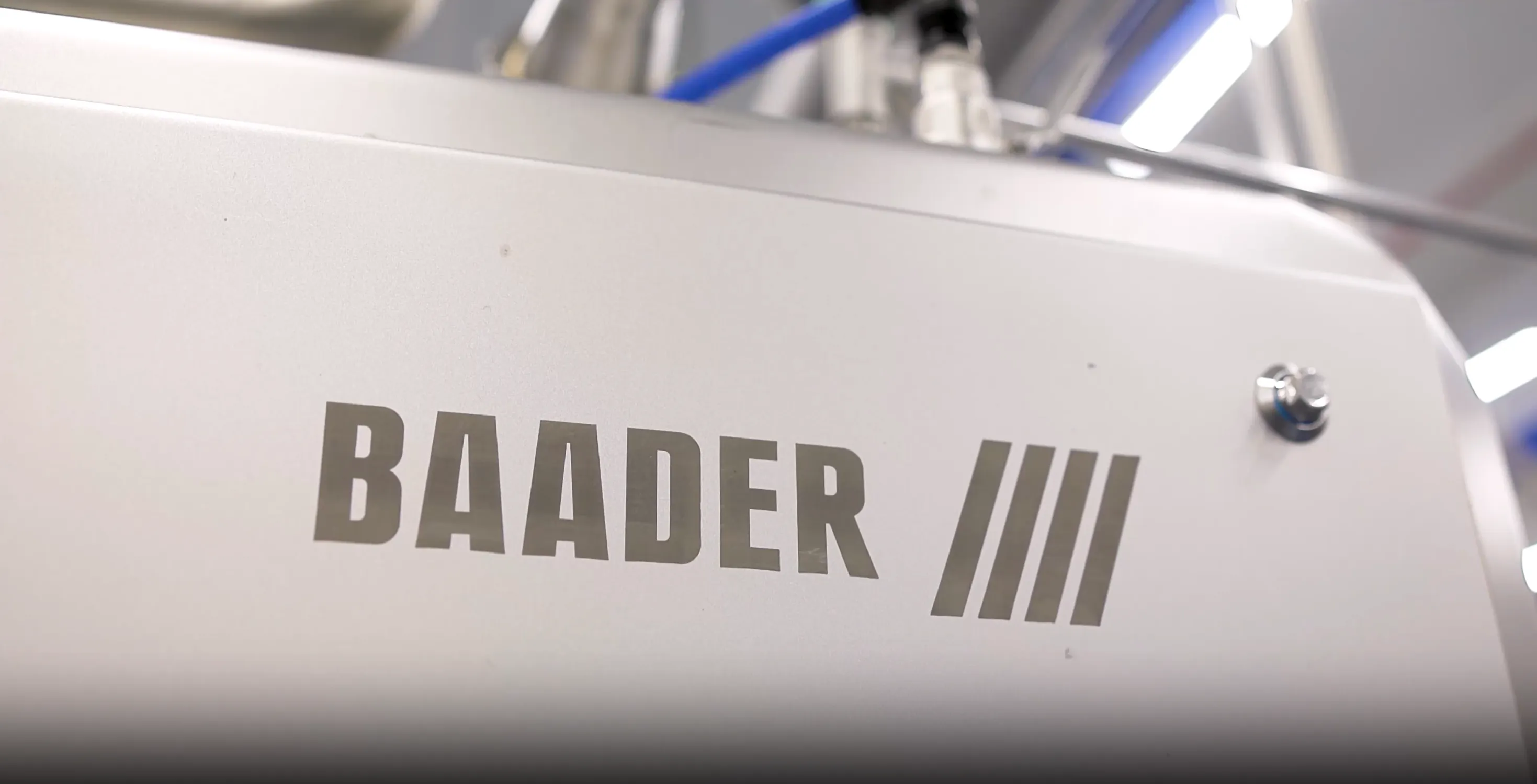 Close-up of a metallic surface with the text BAADER and three stylized vertical lines.