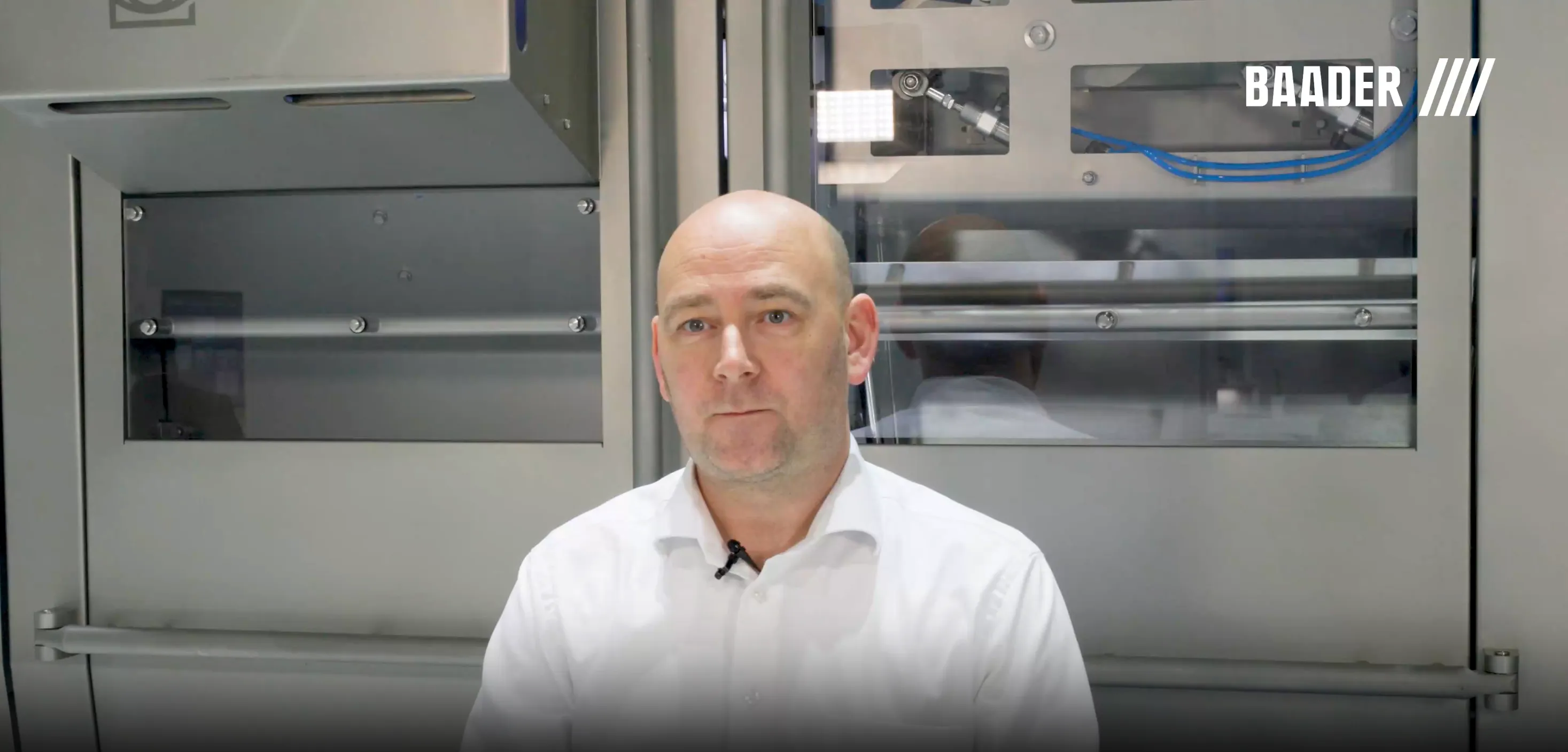 Man in a white shirt sitting in front of industrial machinery with BAADER logo in the background.