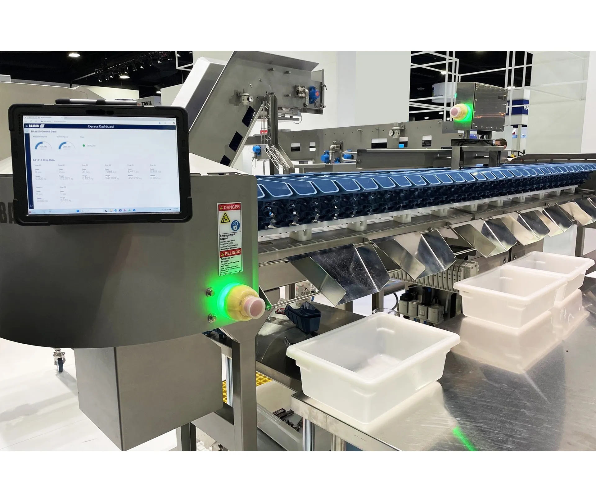 Industrial BAADER sorting machine with a touchscreen control panel displaying data and white plastic bins positioned below blue chutes.