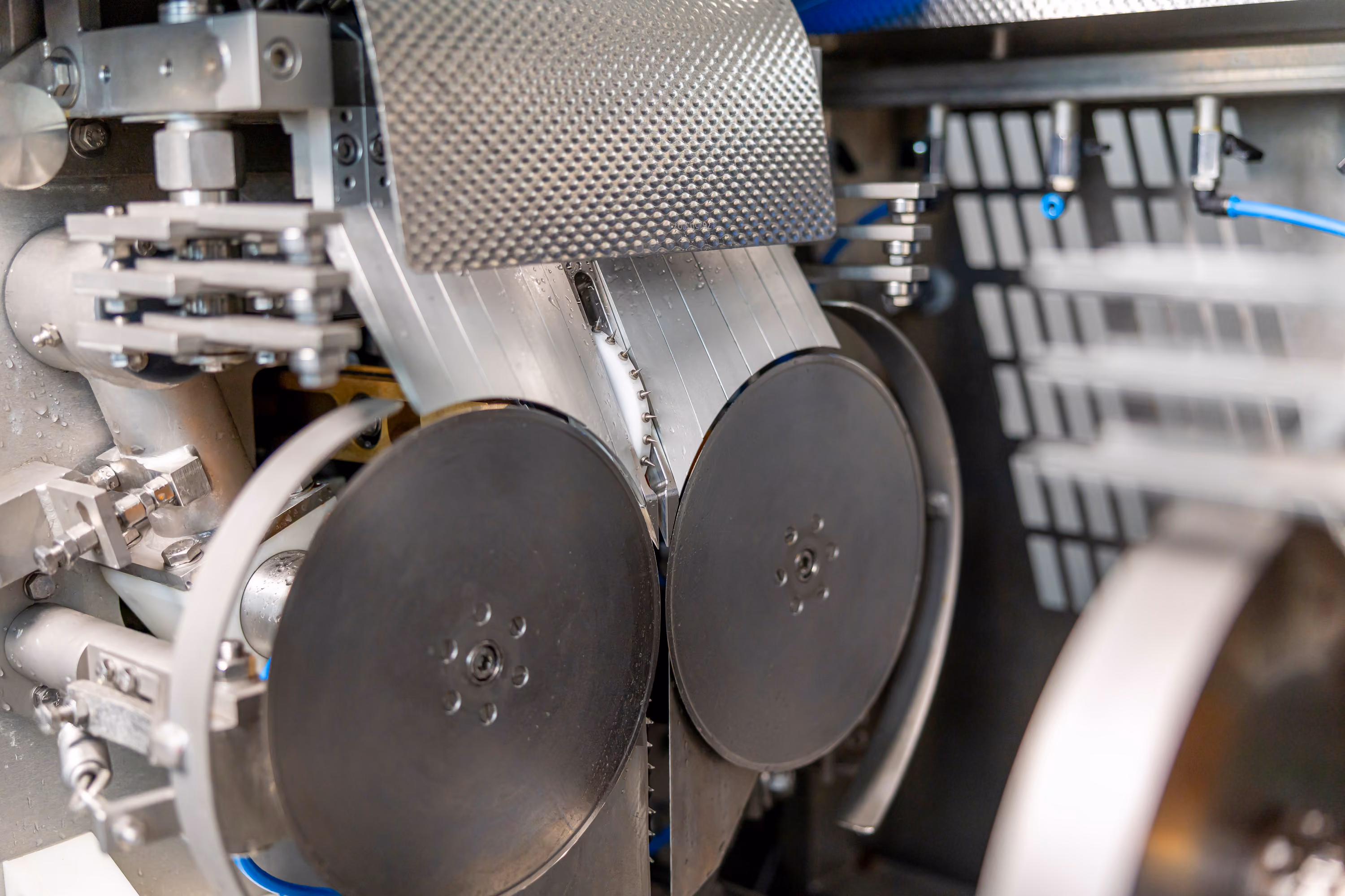 Close-up of industrial machine parts including two large black discs and metal components in a factory setting.