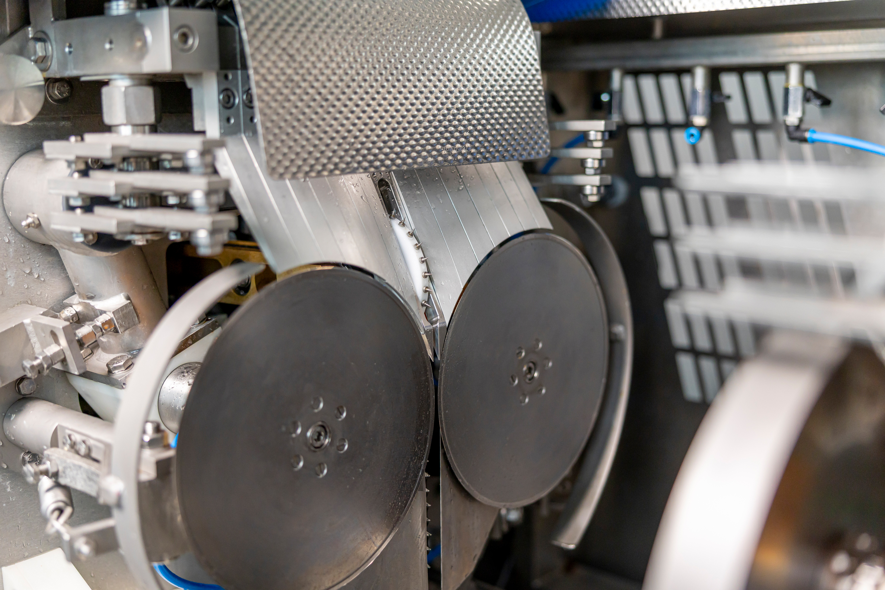 Close-up of industrial machine parts including two large black discs and metal components in a factory setting.