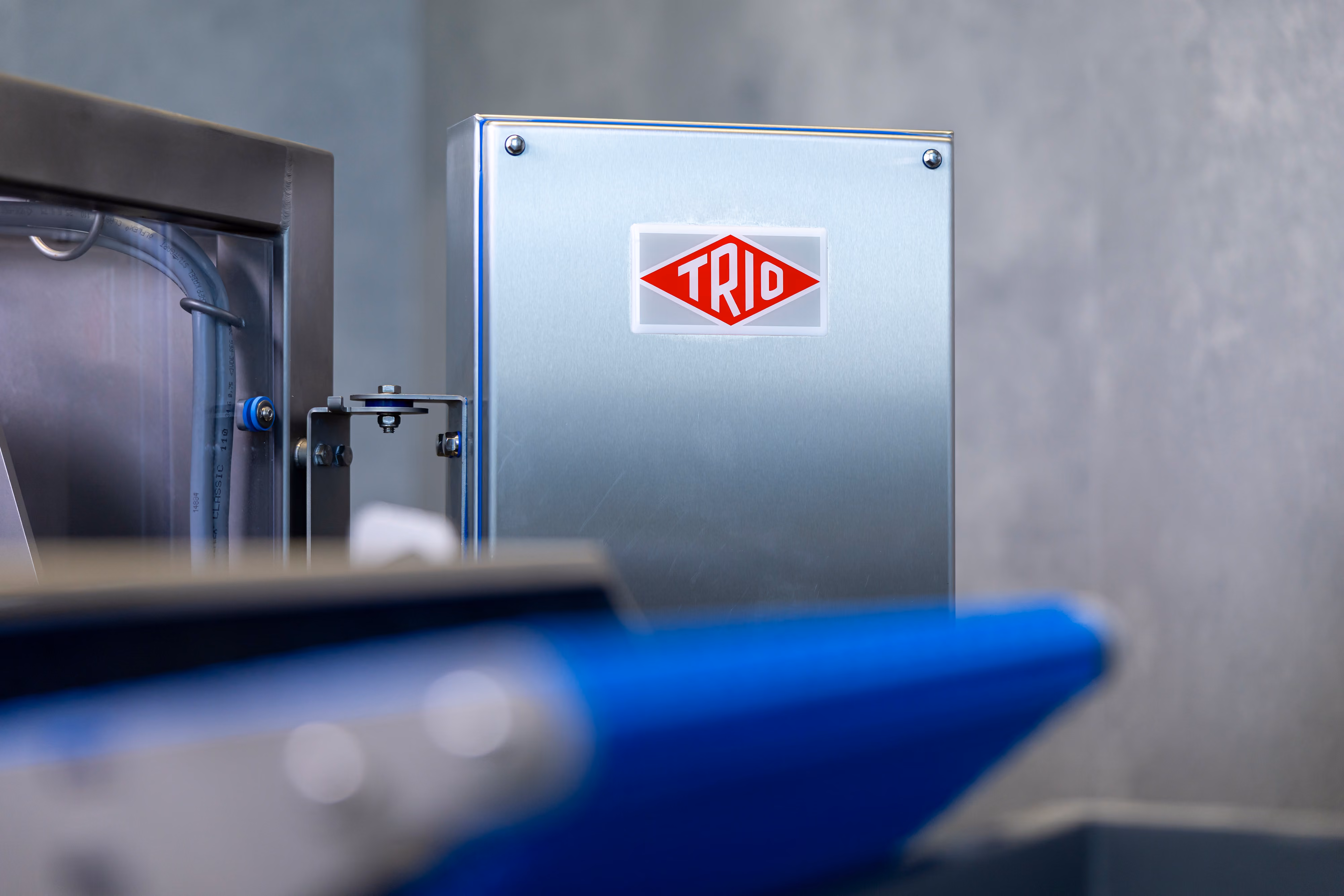Metal industrial equipment panel with red TRIO logo on a gray background.