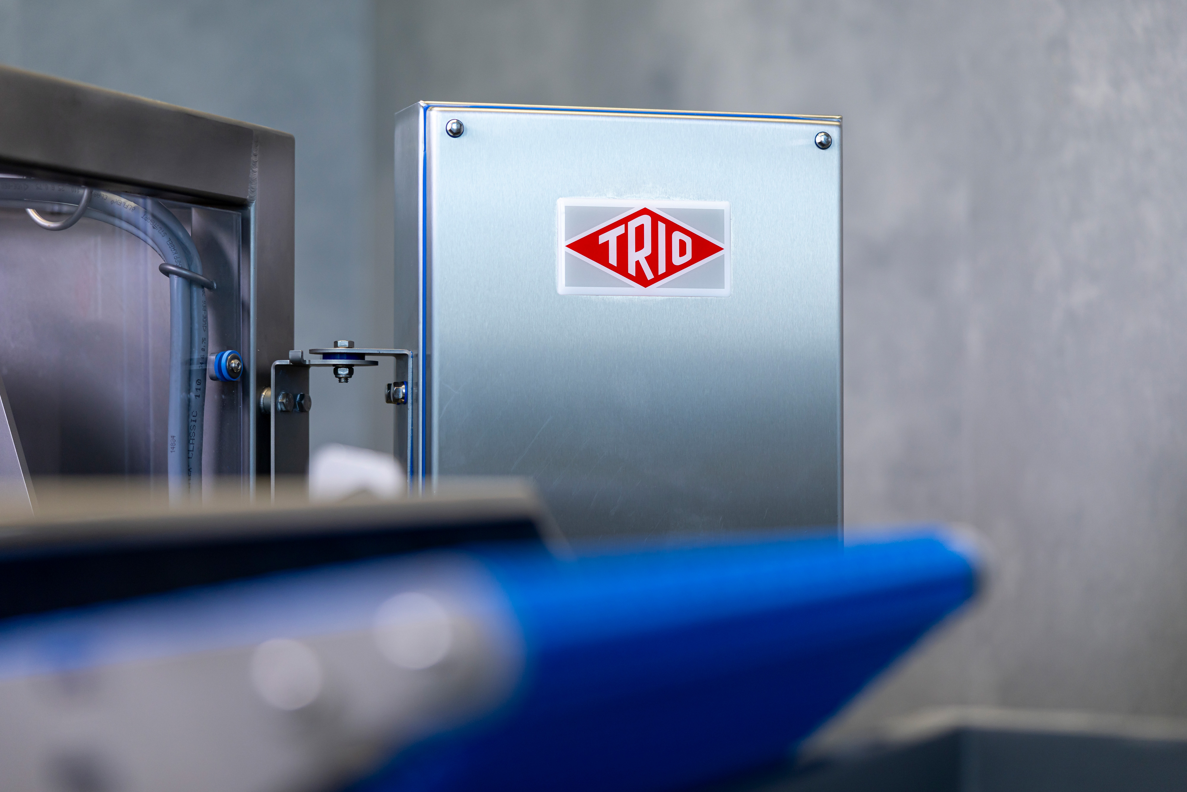 Metal industrial equipment panel with red TRIO logo on a gray background.
