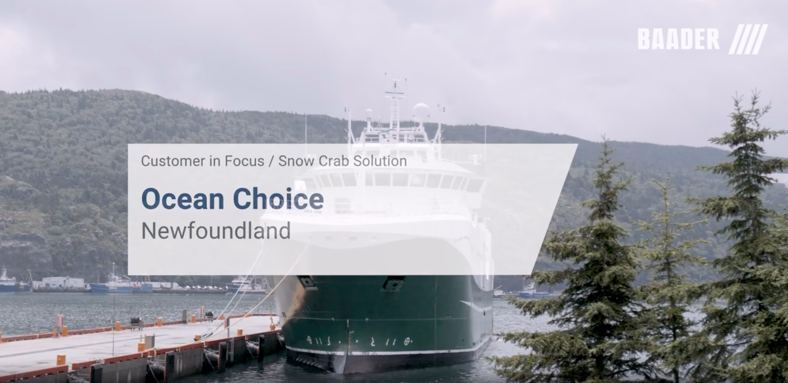 Large green ship docked at a pier with forested hills and waterway in the background, overlaid with text about Ocean Choice in Newfoundland and a Baader logo.