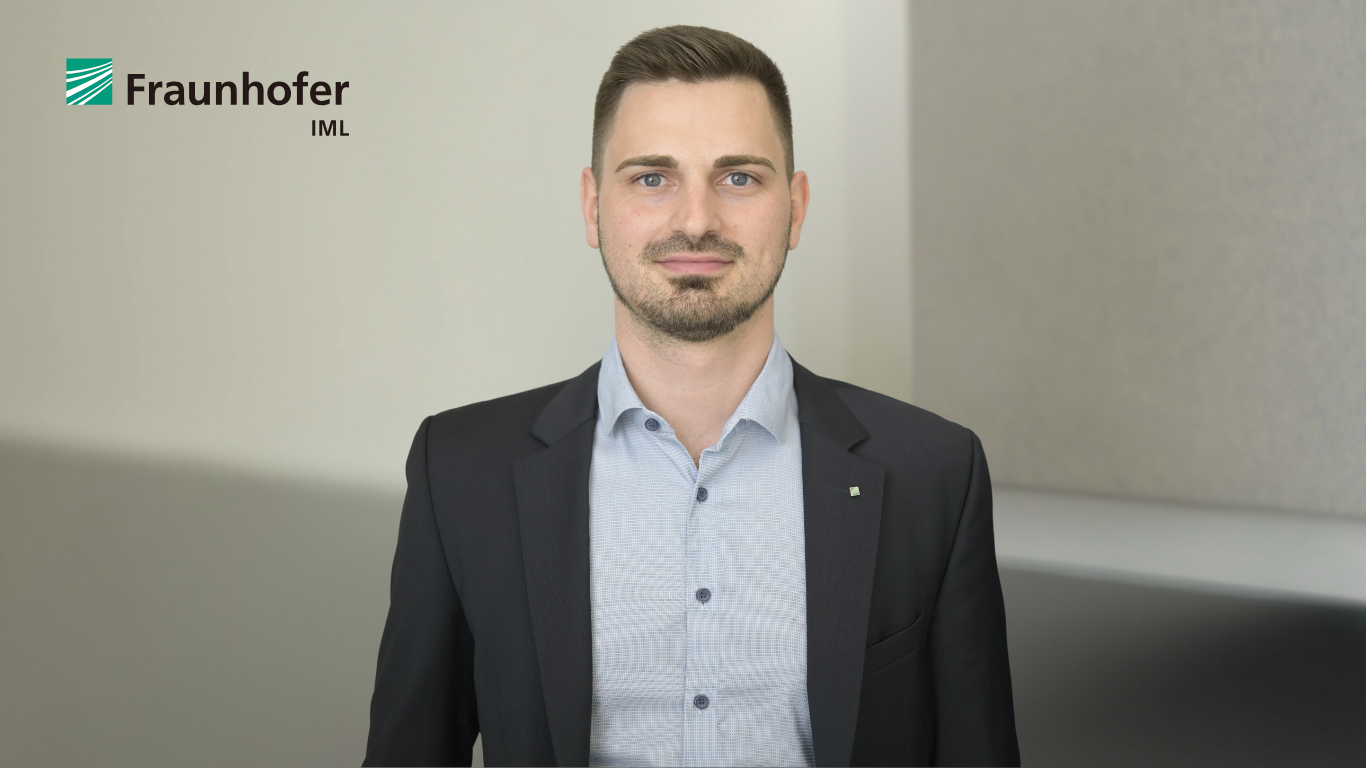 Mann mit kurzem Haar und Bart, trägt ein hellblaues Hemd und ein dunkles Sakko, blickt frontal in die Kamera, neutraler Hintergrund.