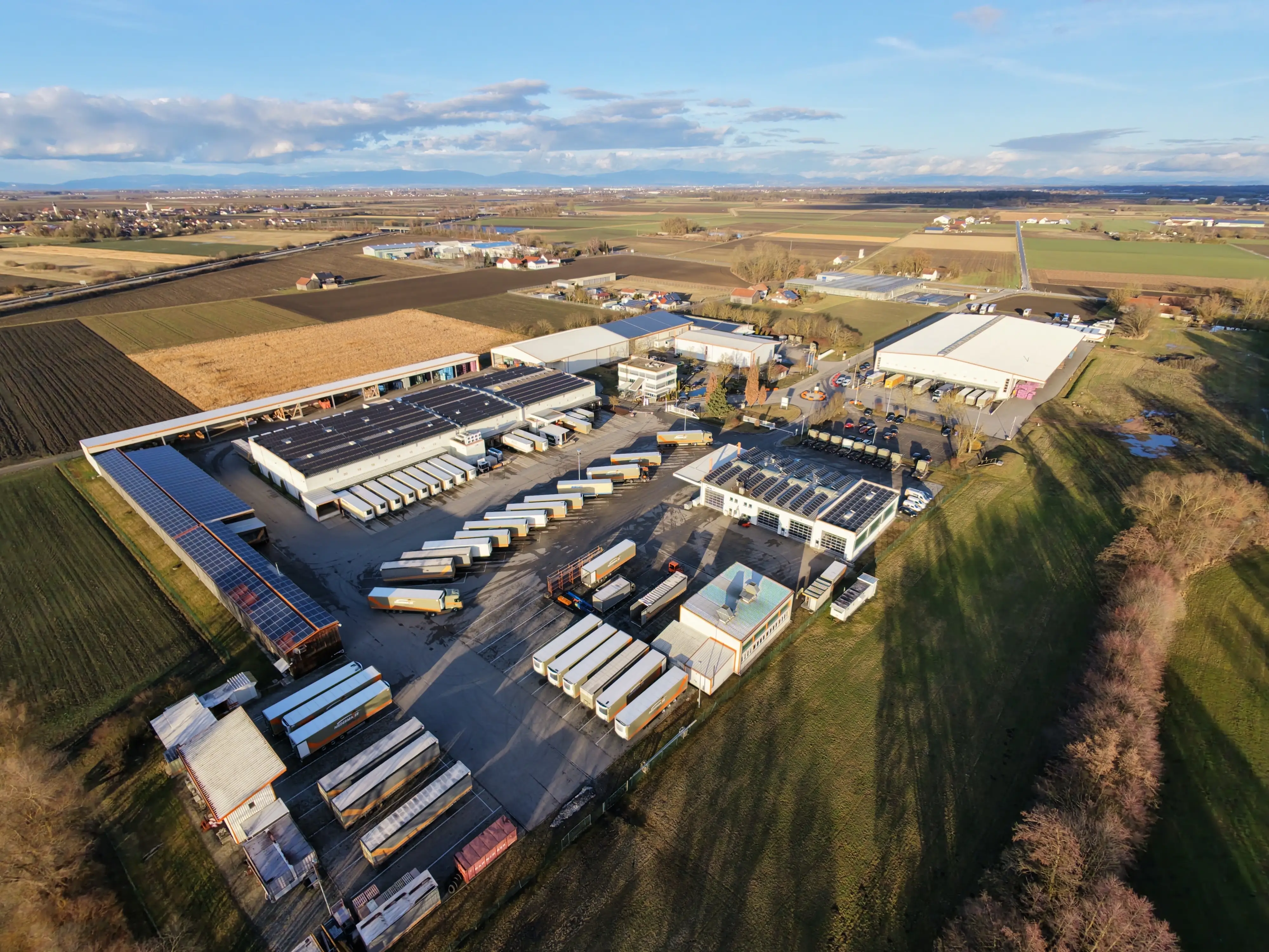Luftaufnahme des Logistikzentrums Niedermaier mit modernen Lagerhallen, Solaranlagen und zahlreichen Lastkraftwagen – ein Beispiel für den Einsatz von Loopario zur Optimierung der Ladungsträgerverwaltung