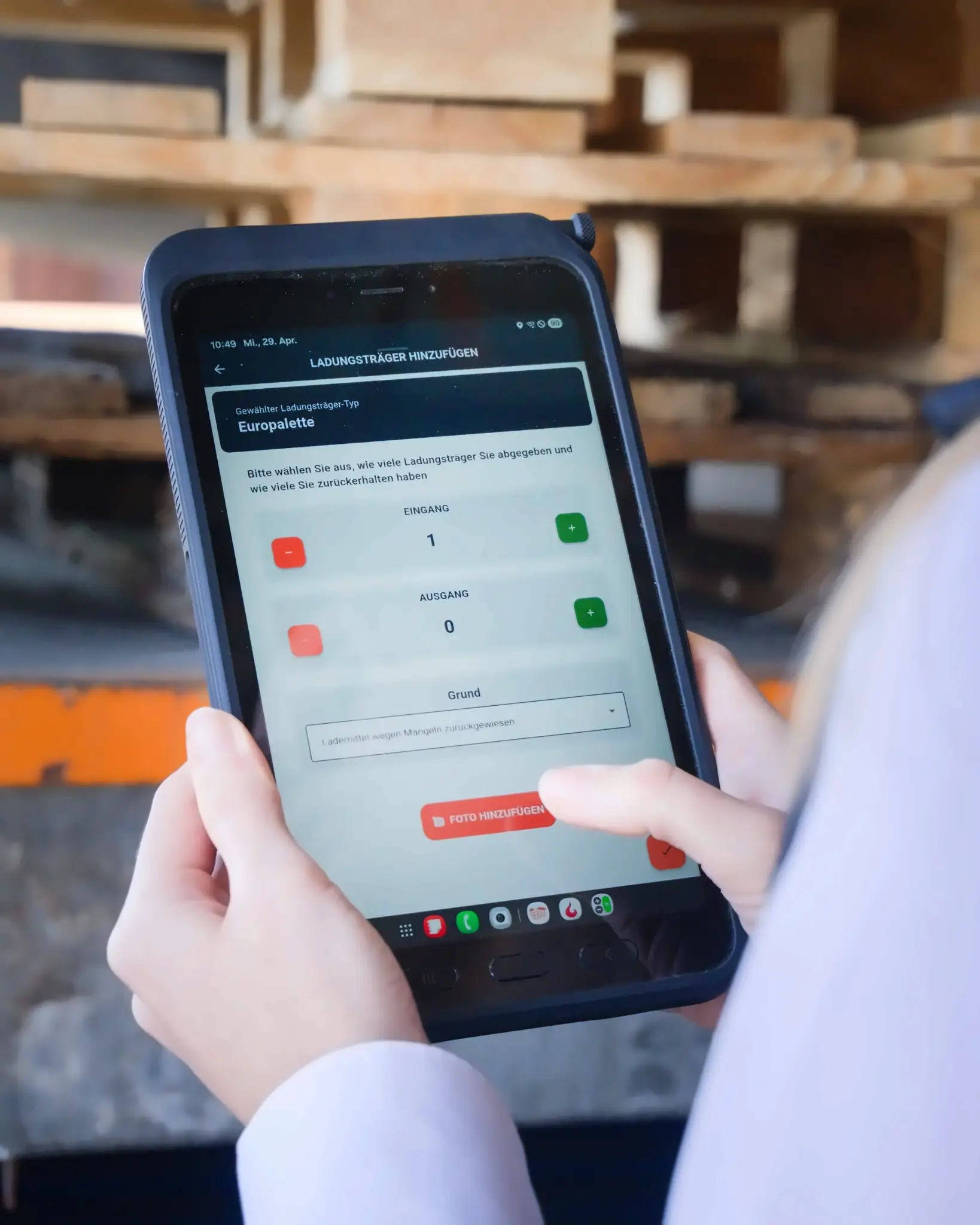 Logistikbude app on a smartphone displaying the interface for adding load carriers, with fields for carrier type (euro pallet), quantities (inbound/outbound), and reason