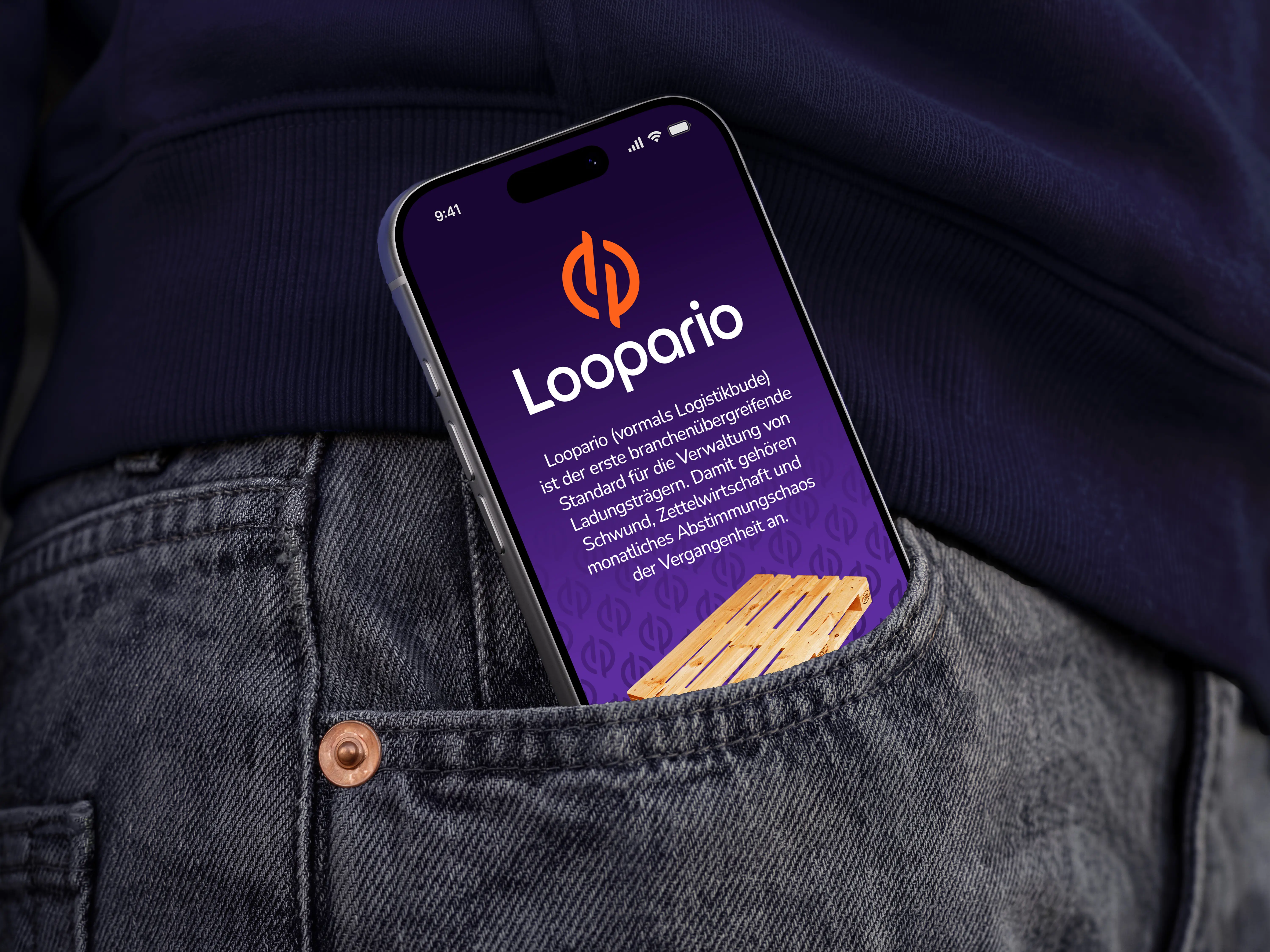 Smartphone in the back pocket of jeans displaying the Loopario screen with orange logo and white text on a dark purple background. Lifestyle product photo.