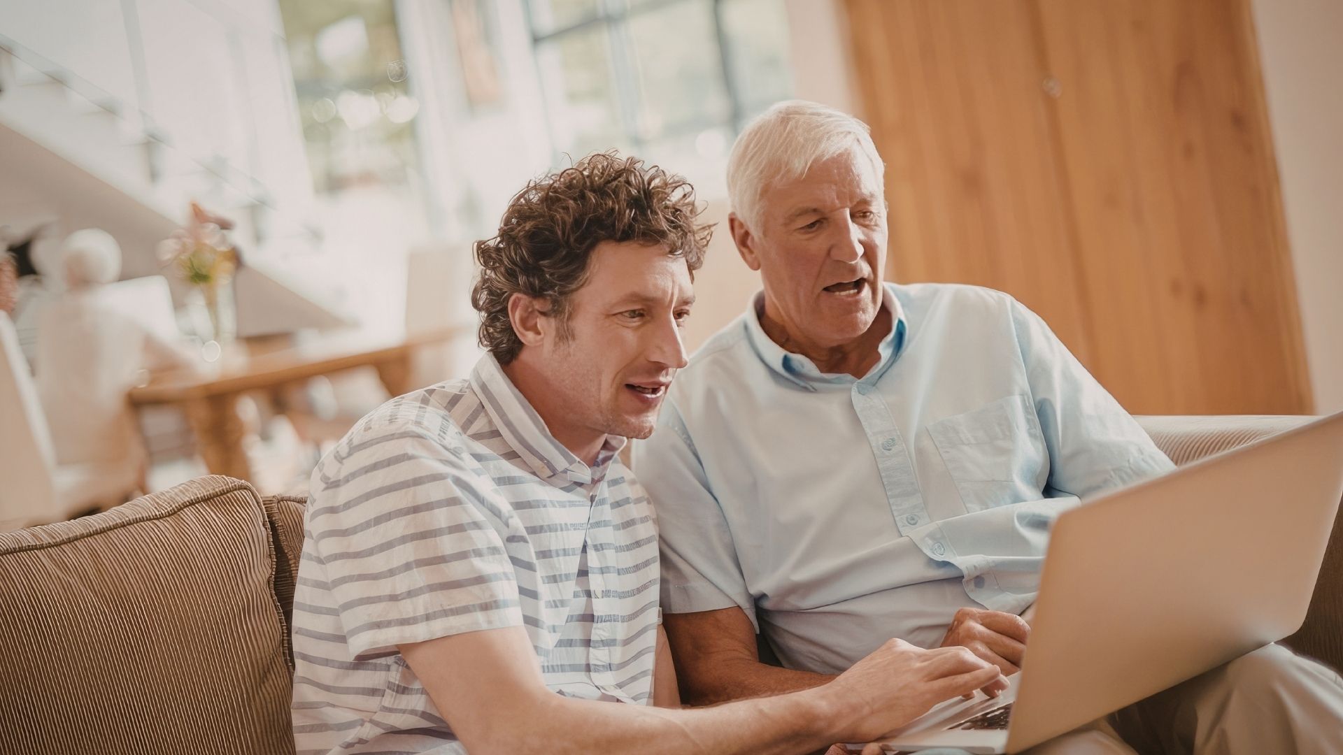 Jongere en oudere man samen op de bank met laptop