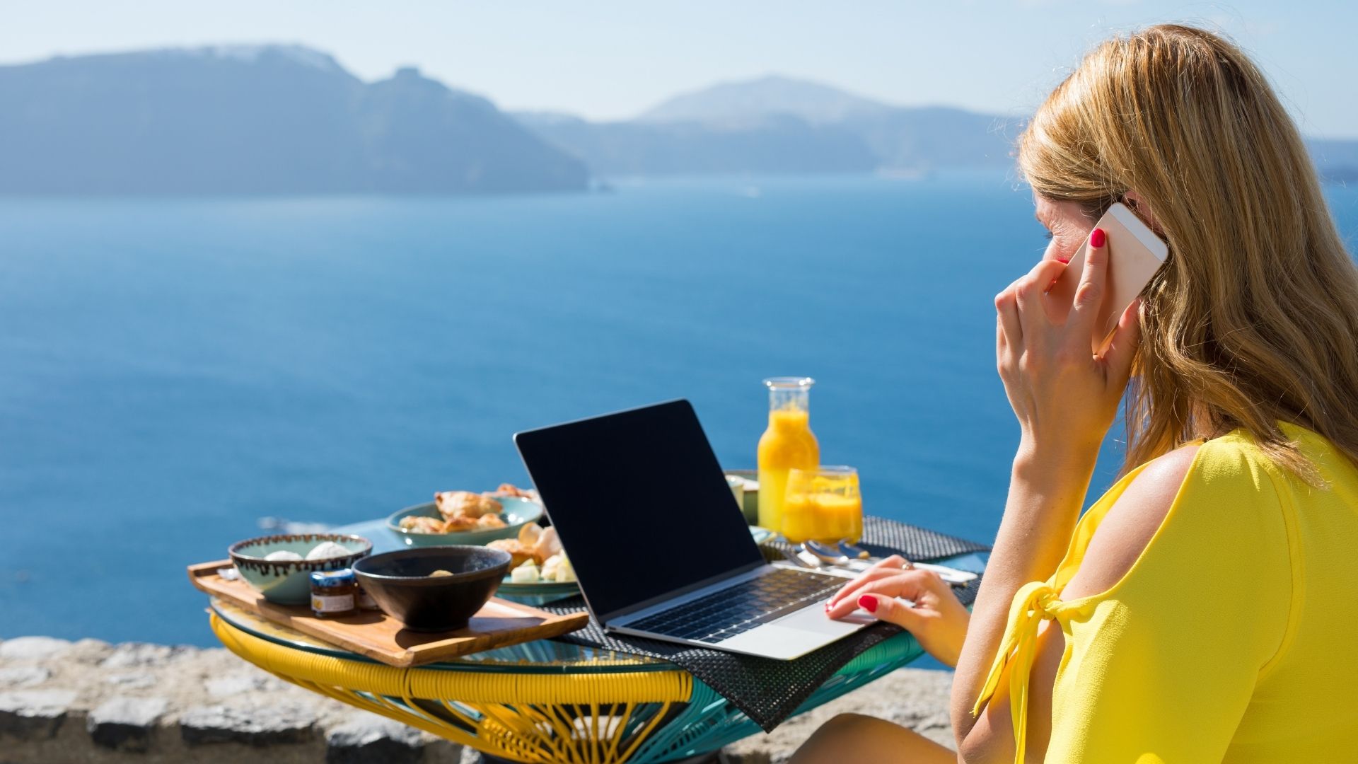 Vrouw op mooie locatie bellend achter laptop