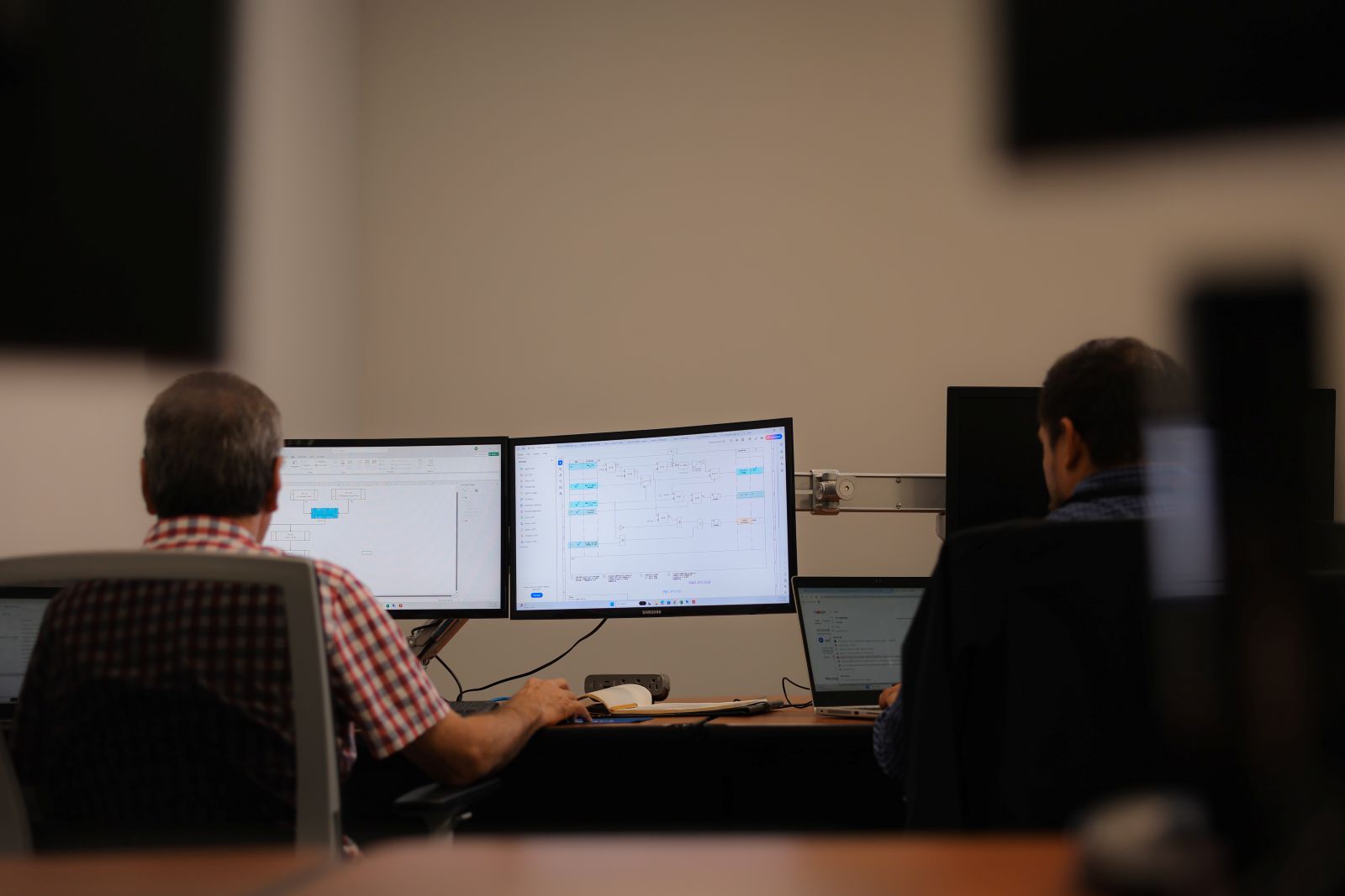 a group of men sitting at a desk with computers
