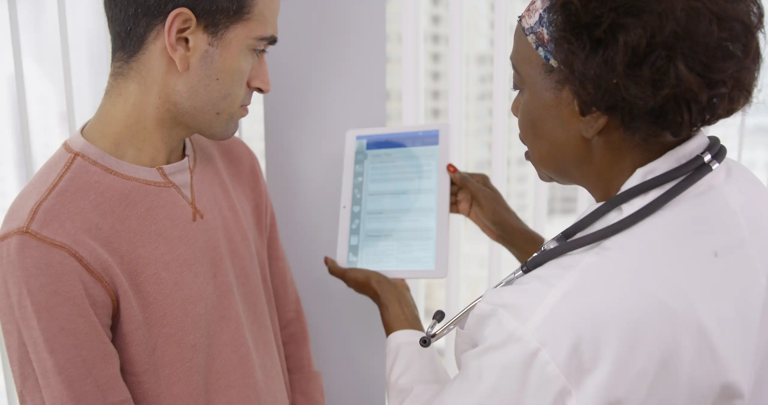 A physician shares preoperative data results with patient on tablet