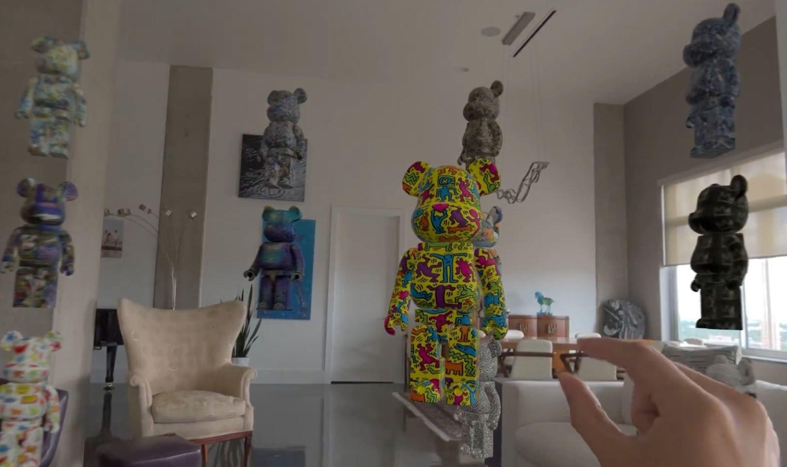 Several patterned Bearbrick figures, 1 person-sized, placed around a real living room beside a sofa and a lamp.