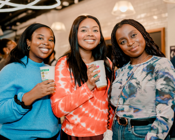 Three ladies smiling, holding Wray & Nephew cups