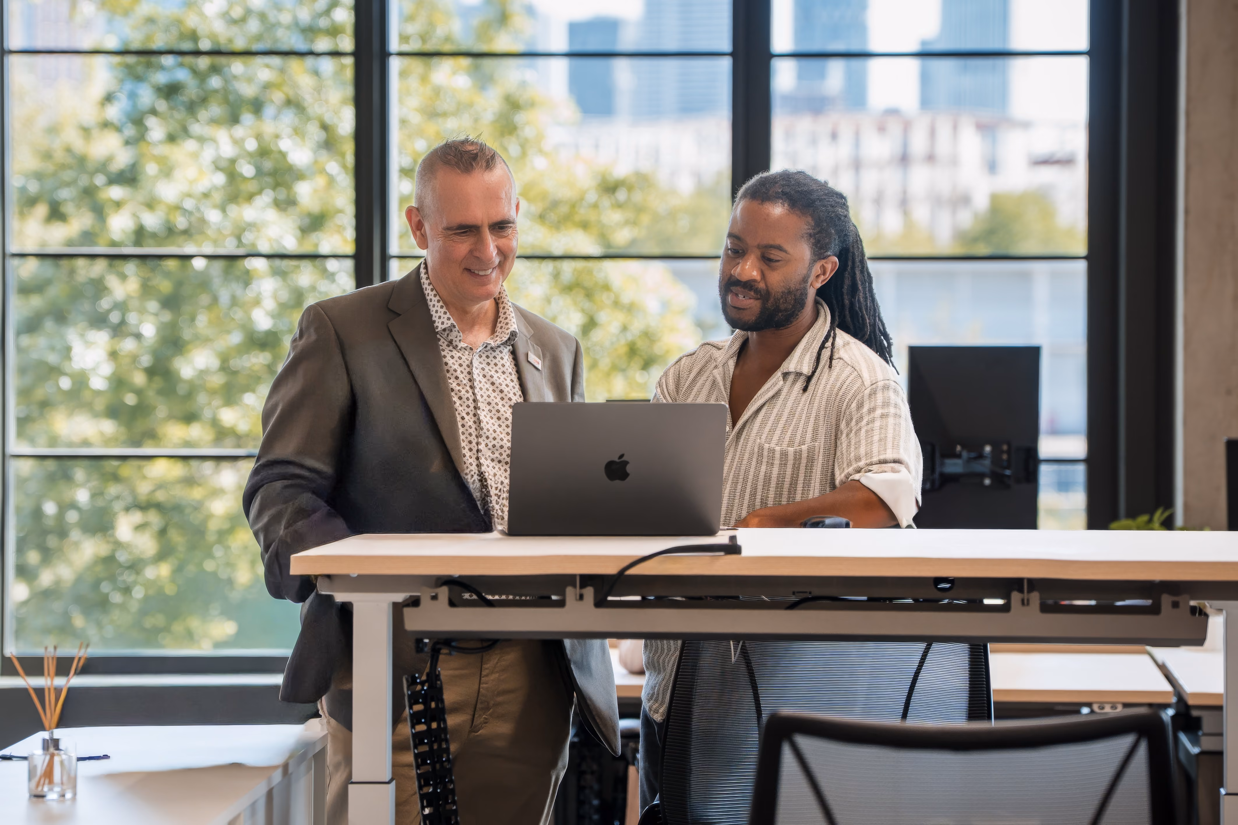 Two men standing behind a desk working together on a laptop