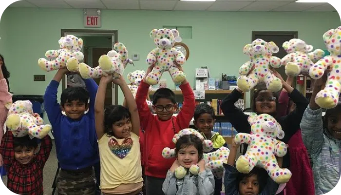 Kids happily showing off stuffed animals in classroom.