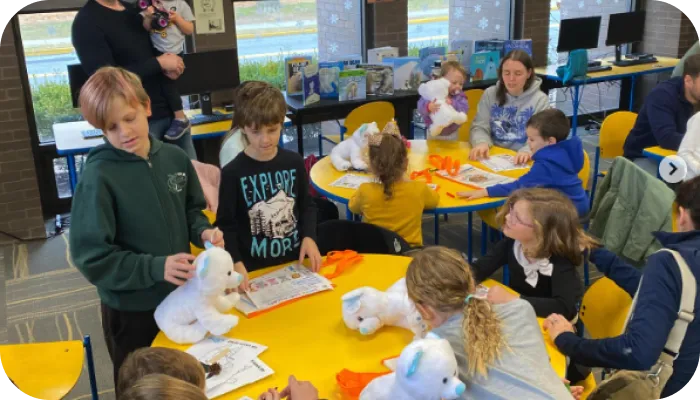Children sitting around a table with stuffed animals, engaging in imaginative play and fostering social interaction.