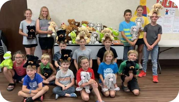 Group of kids smiling while holding their favorite stuffed animals.