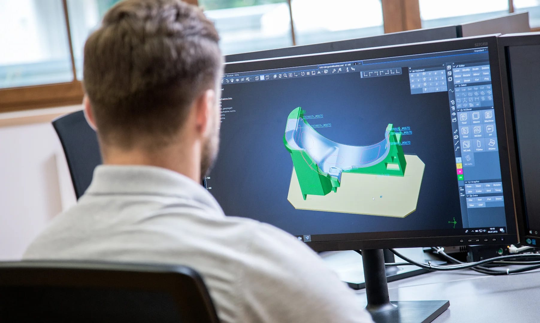 Mann sitzt vor einem Bildschirm und betrachtet eine 3D-Konstruktion