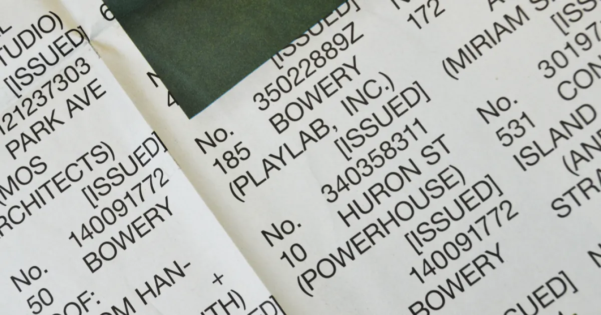 Close-up of printed paper with text listing various building addresses and company names including Bowery and Playlab, Inc.