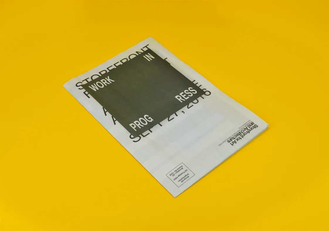 Folded black and white printed brochure titled Work in Progress on a yellow background.