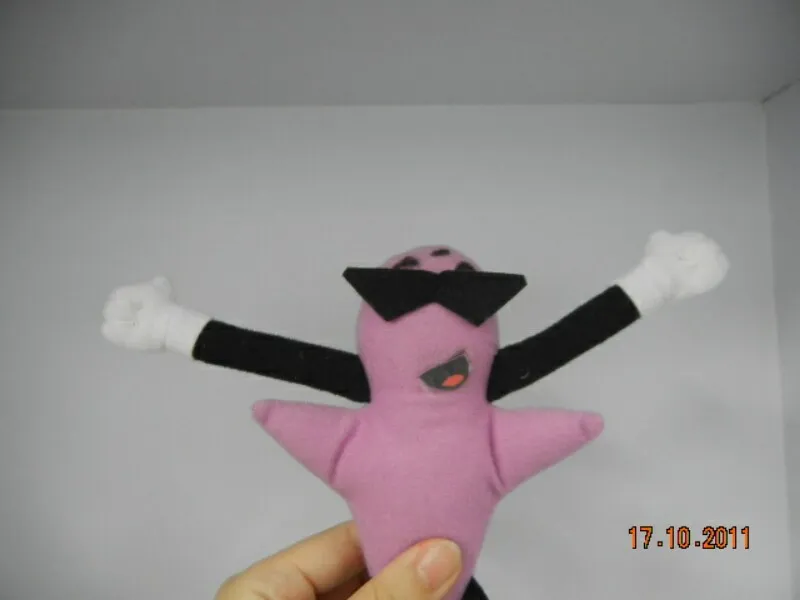Hand holding a purple plush toy with black triangular sunglasses, black arms, and white gloves against a plain background.