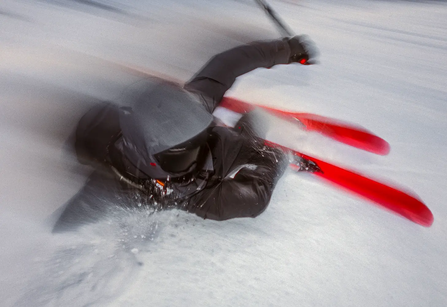 A skier turning in deep powder on red skis