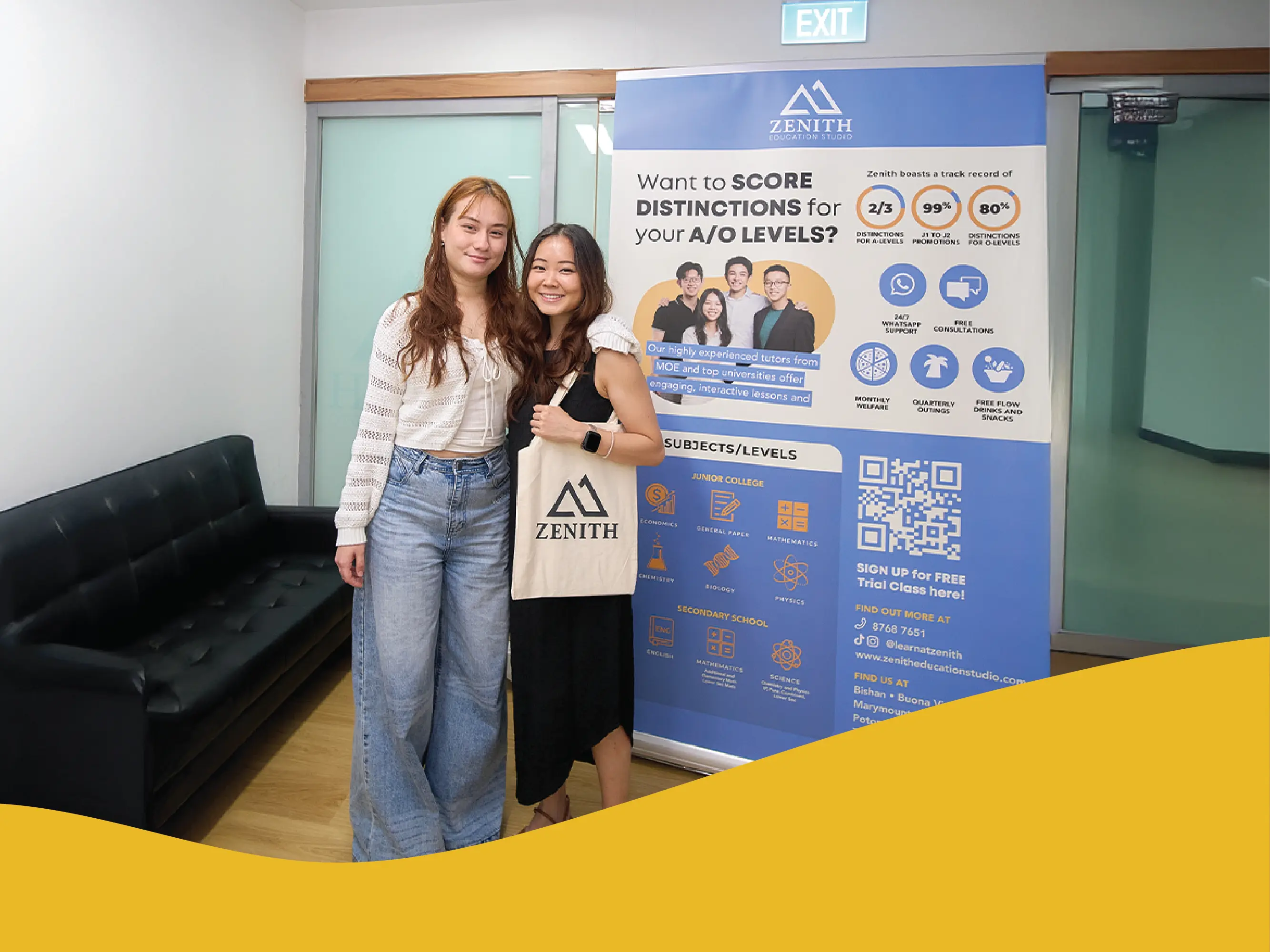 Student and teacher standing side by side indoors, smiling at the camera. One holds a tote bag with the Zenith logo. They are next to a tall Zenith Education Studio banner.