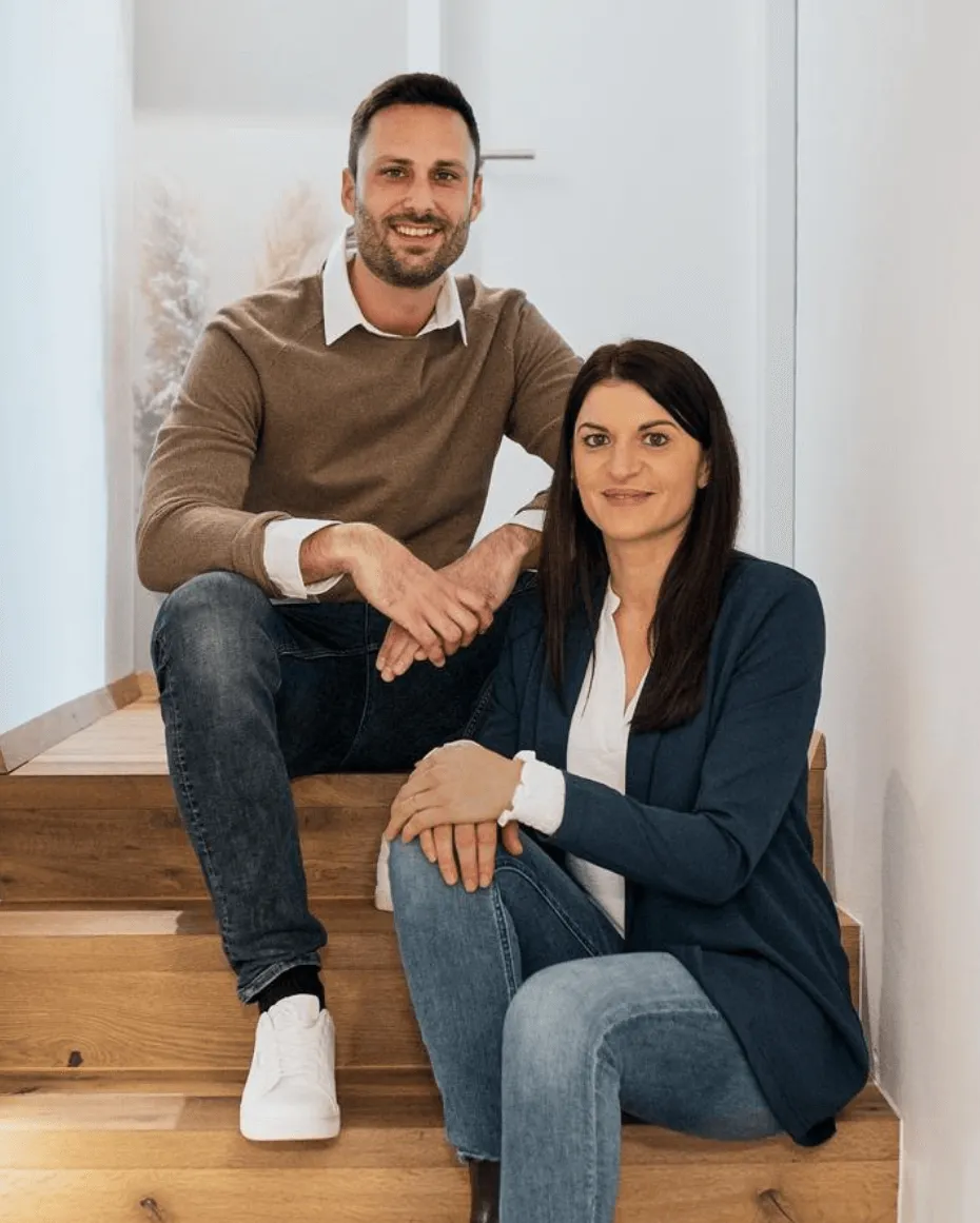 Ronny und Maria sitzen auf einer Treppe und sehen dich an 