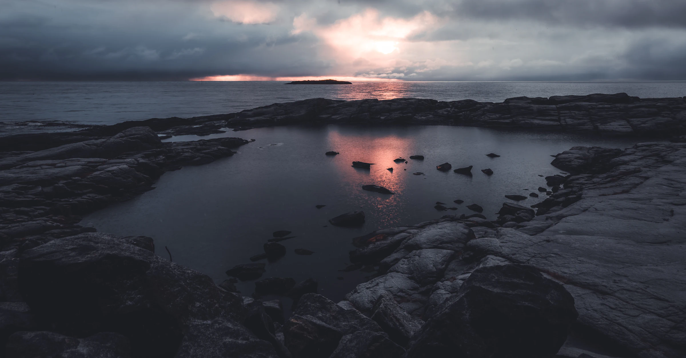 Dark rocky shoreline in Lofoten under a low winter sun