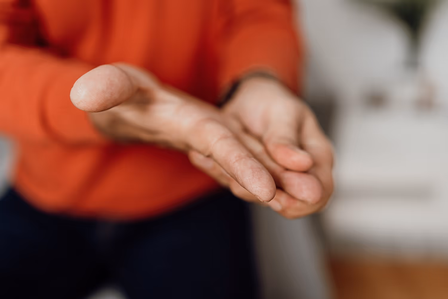 Bildet viser en person som tar seg til noen fingre tilsynelatende på grunn av nummenhet i fingrene, kanskje relatert til et skiveprolaps eller nerverotspåvirkning i nakken, cervikal-kolumna.