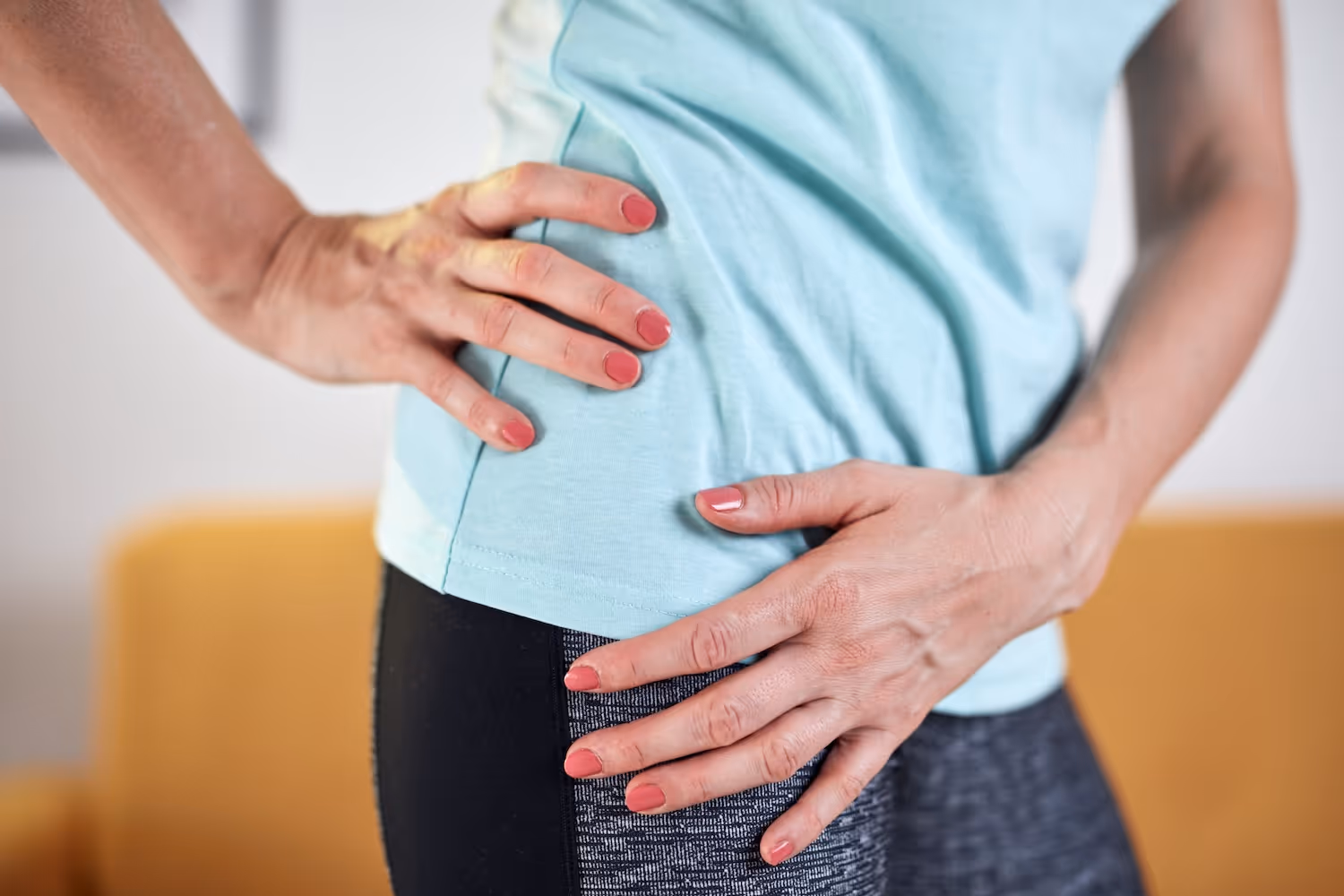 bildet viser en eldre kvinne som holder seg til utsiden av hoften, kanskje relatert til smerter i trokanter området, for eksempel en skade relatert til trokantertendinopati eller slimposebetennelse i trokanter eller hofte. 