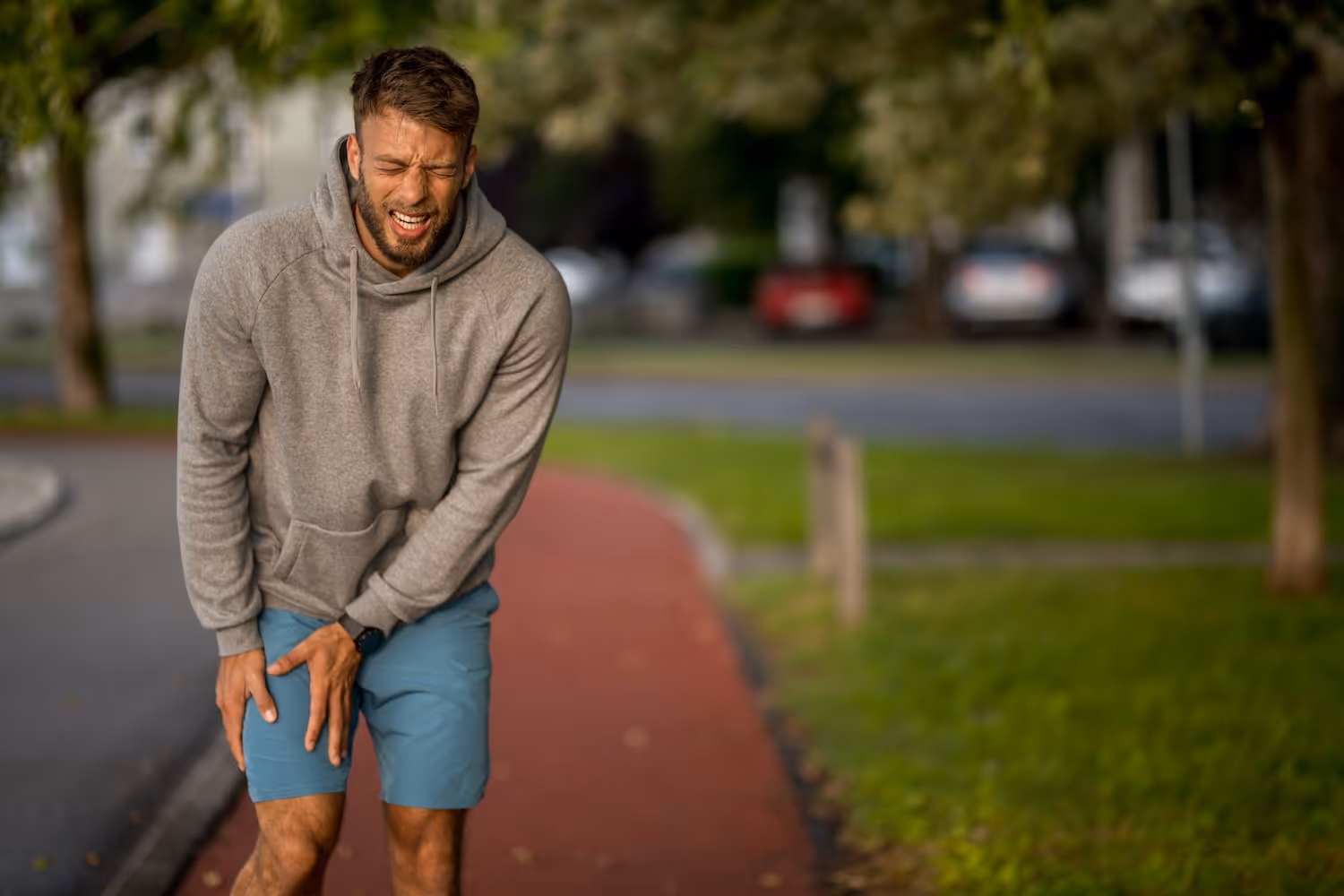 bildet viser en atletisk ung mann ute på løpetur som holder seg til lyske og framside lår på grunn av labrumskade i hofteleddet. 