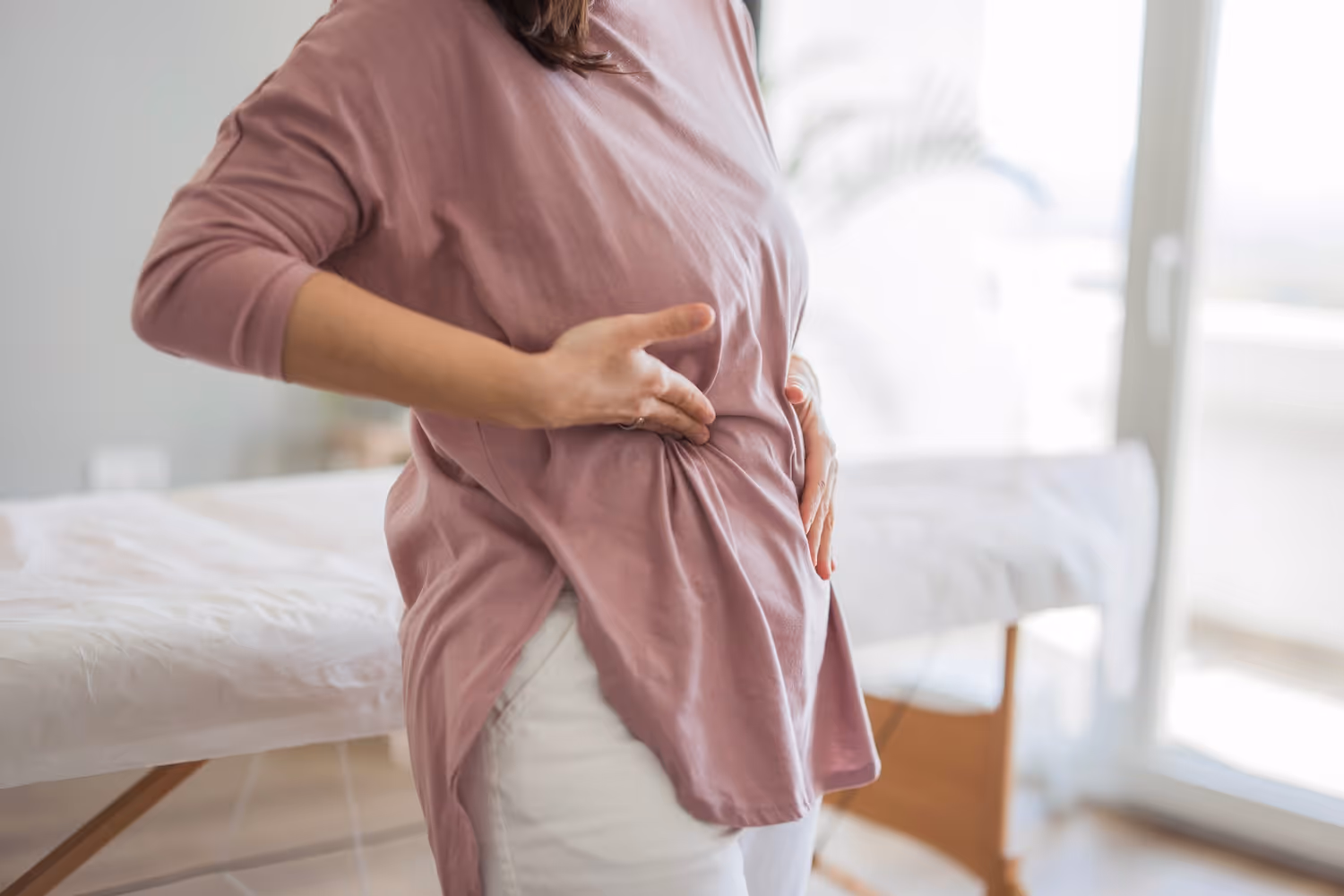 bildet viser en kvinne som holder seg til siden av brystkassen, mest sannsynlig på grunn av smerter i et ribbein eller på grunn av smerter fra brystryggen som stråler framover.